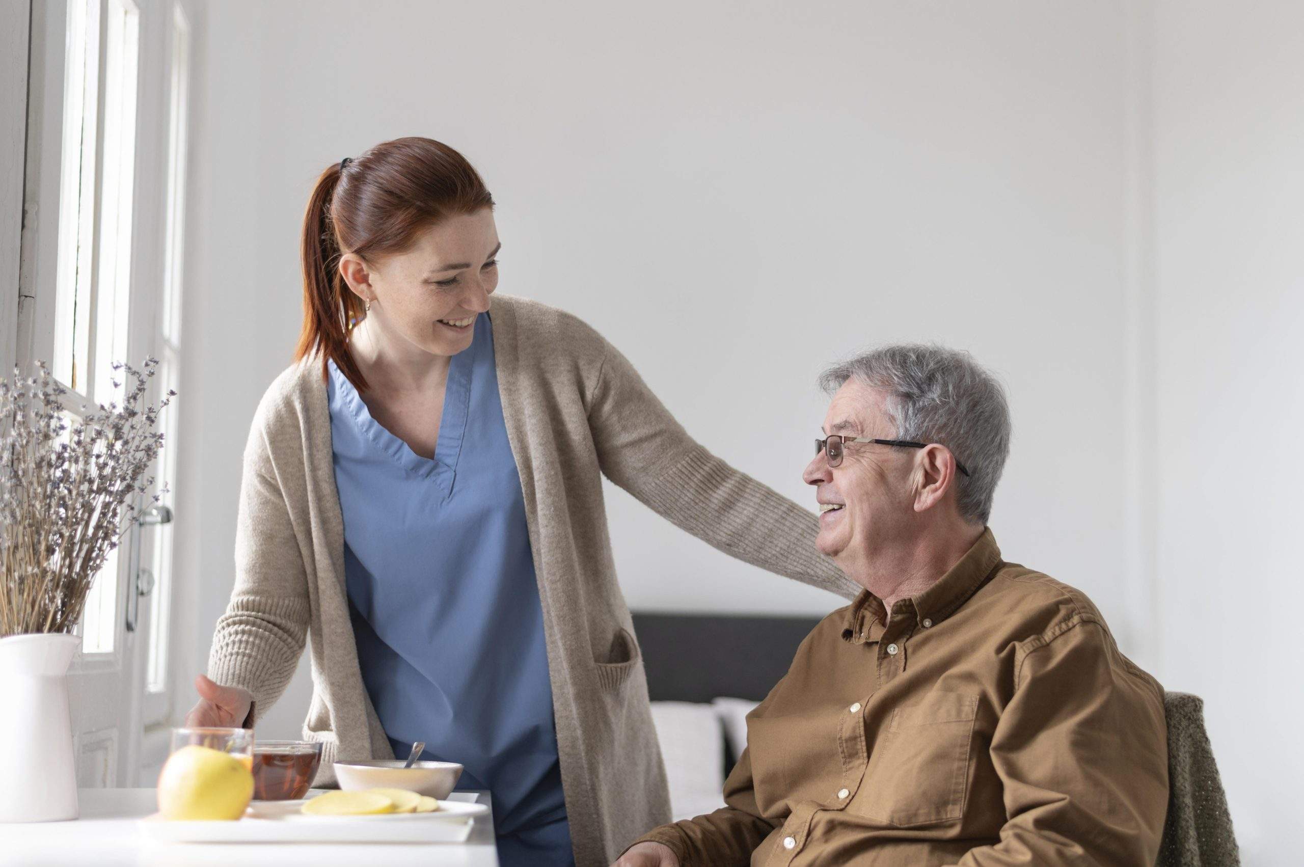 social care nurse keeping a patient company, both are smiling